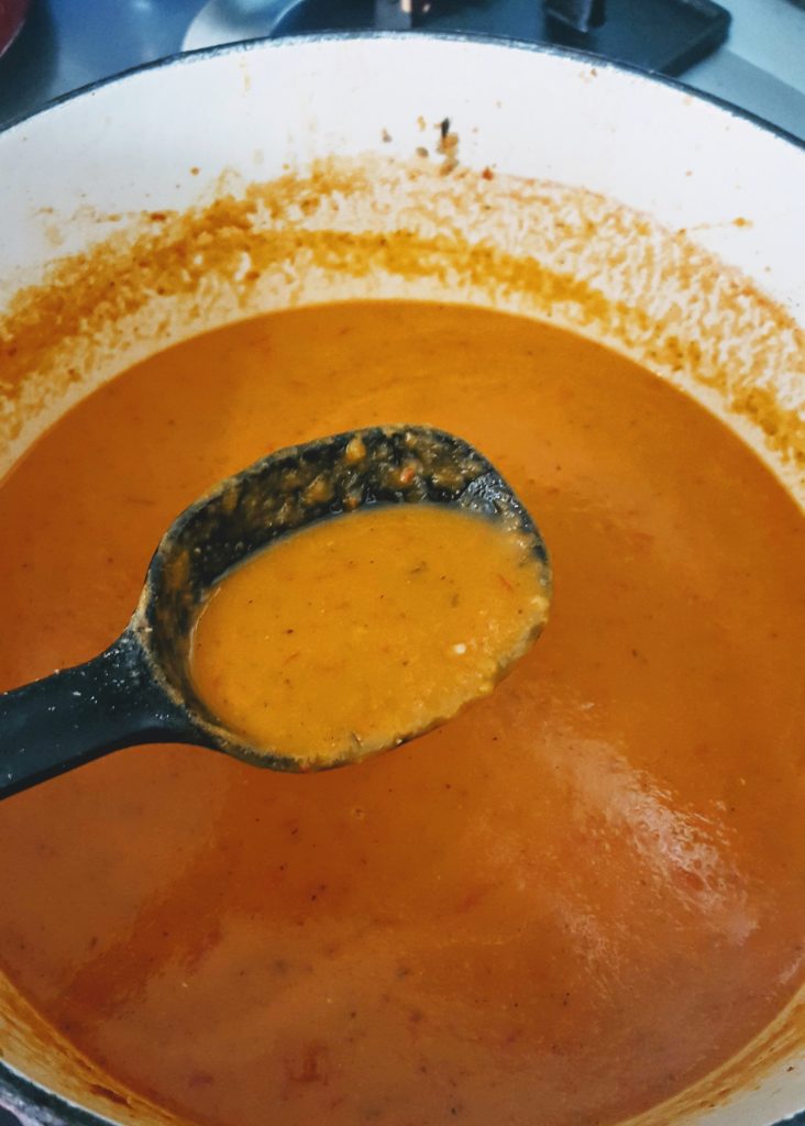 cream of tomato soup in pot with ladle 