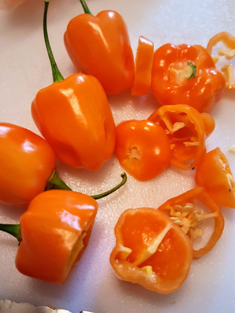 whole and sliced orange habanero peppers