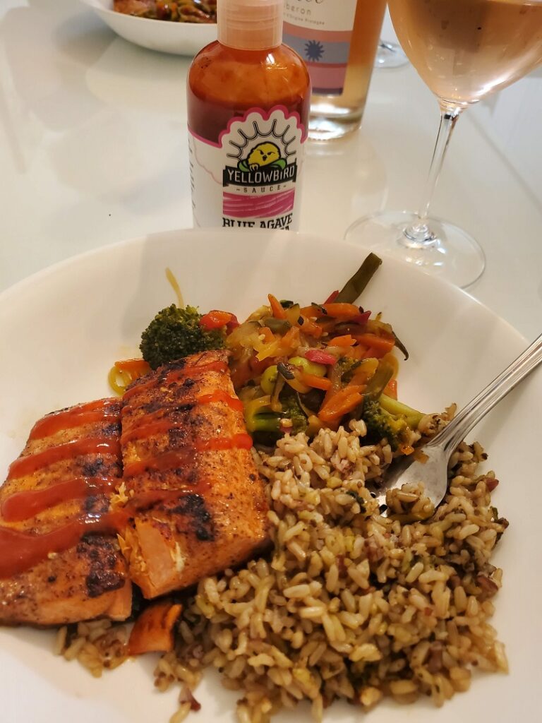 sriracha salmon and rice dish with bottle of hot sauce