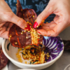 closeup of woman's hands de-seeding a dried chile pepper over bowl